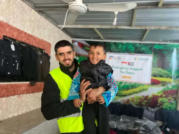 A CBB volunteer holds a child at an emergency support distribution