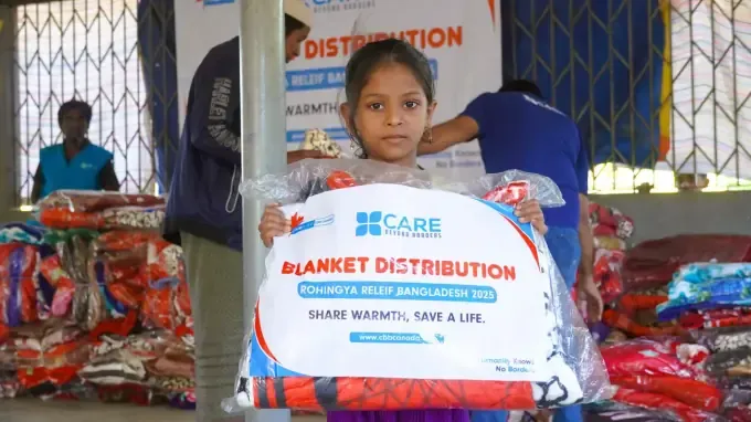 A girl holds a CBB blanket-distribution pack