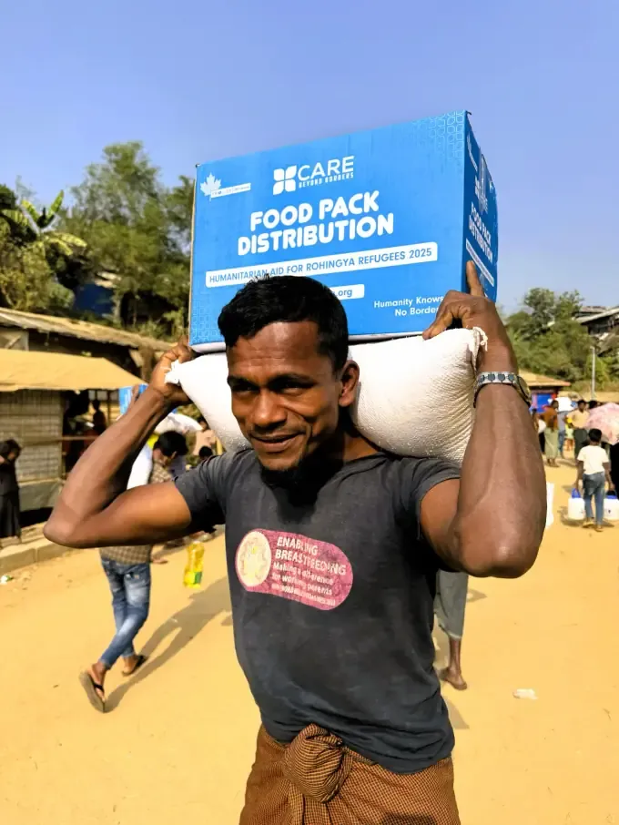 A man carries a CBB food pack home at a distribution in Bangladesh