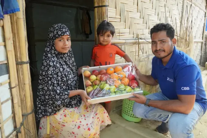 A woman and boy receive a box of fresh produce from CBB