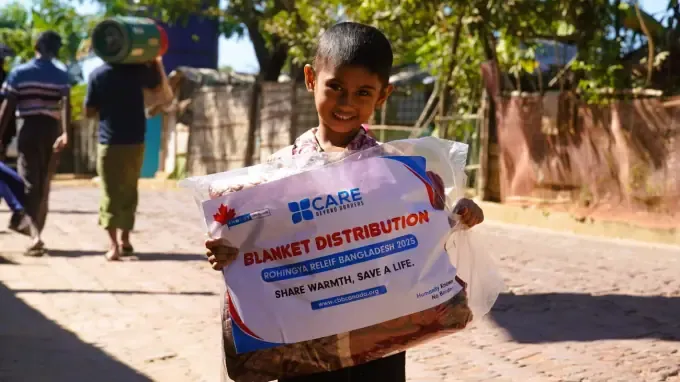 A boy holds a CBB winter blanket pack