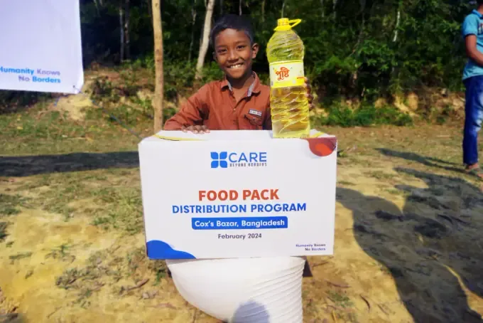 A boy holding a CBB food pack of oil and staples