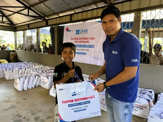 A CBB volunteer gives a boy a gift at a clothes distribution