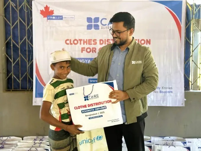 A boy holds a certificate at a CBB clothes distribution for orphans