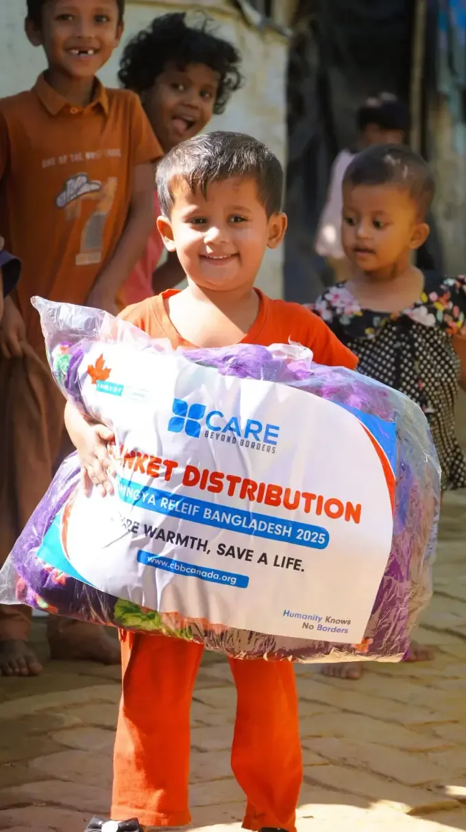Two girls hold CBB blanket-distribution packs
