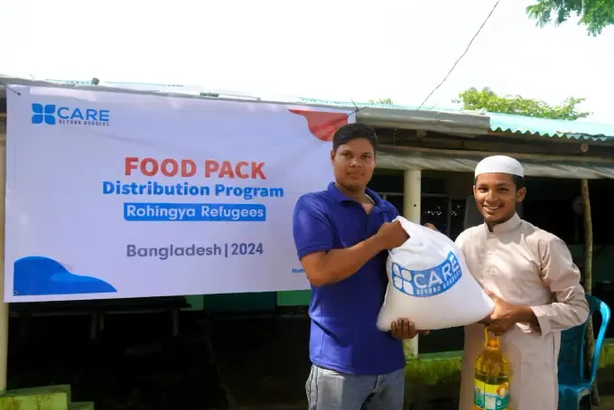 A CBB volunteer hands a food pack to a recipient in Bangladesh