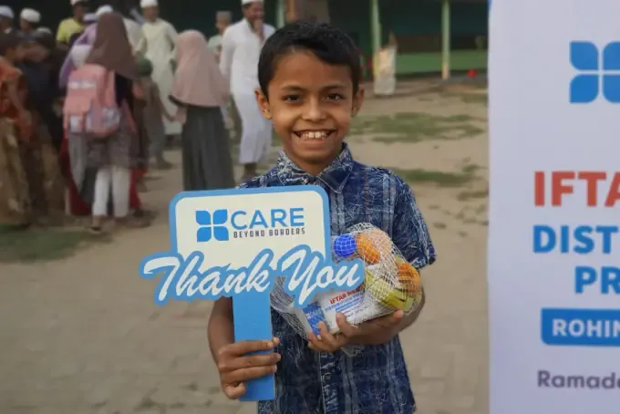 A smiling boy beside a CBB 'Thank You' distribution banner