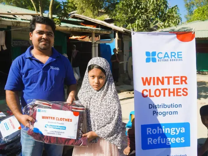 A CBB volunteer hands a winter pack to a girl