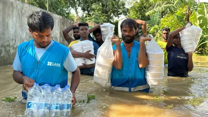 A CBB volunteer carries relief sacks through a flood