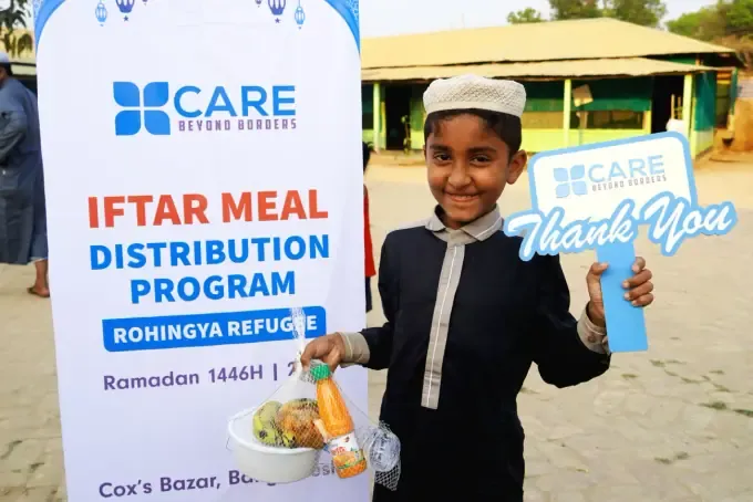 A boy holding a CBB iftar food pack bag