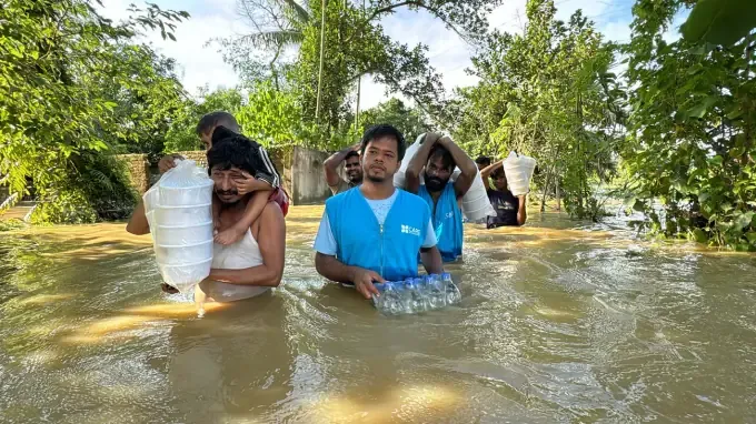 CBB volunteers wade through floodwater with relief supplies