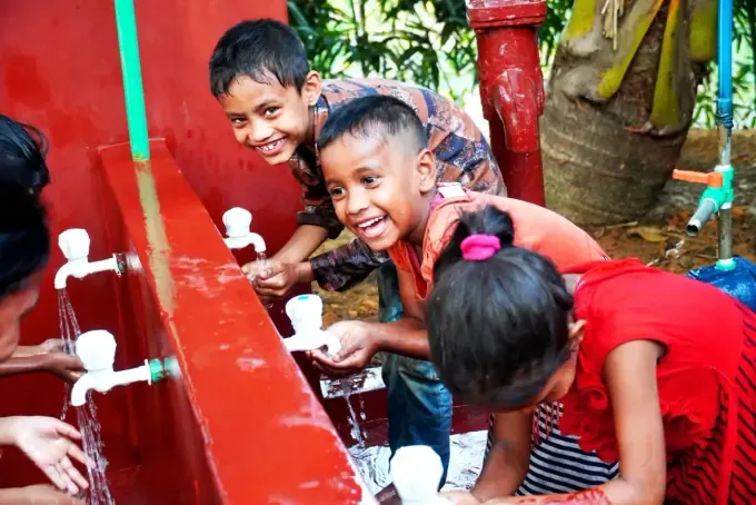 Two boys smile beside a CBB clean-water pump