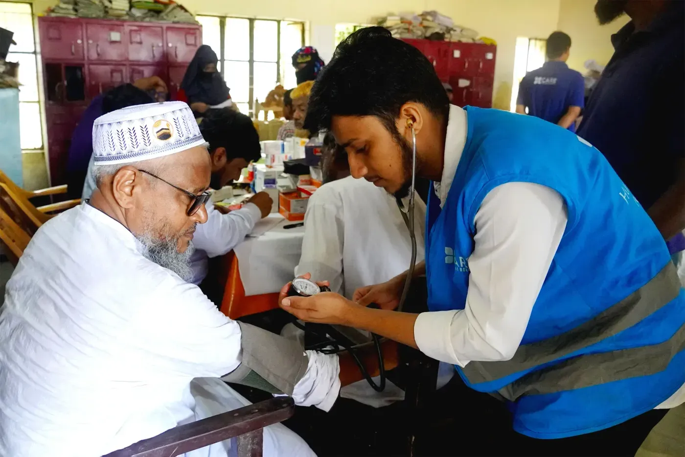 A CBB Canada health worker checking an elderly patient's blood pressure at a medical camp