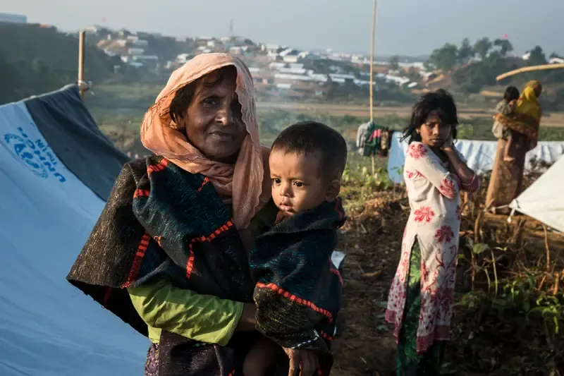 A family wrapped in blankets against the cold inside a thin-walled shelter in winter